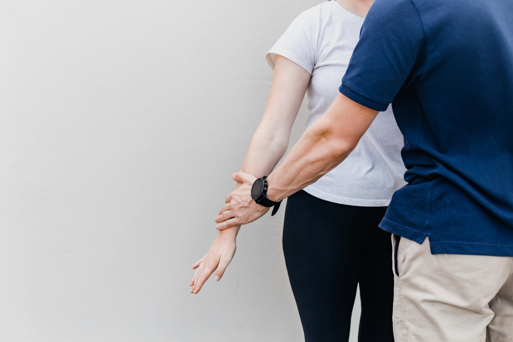 Physiotherapeutin unterstützt einen Patienten bei einer Beinübung mit Widerstandsband